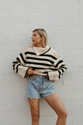 a lady in a striped loose sweater and a pair of denim shorts